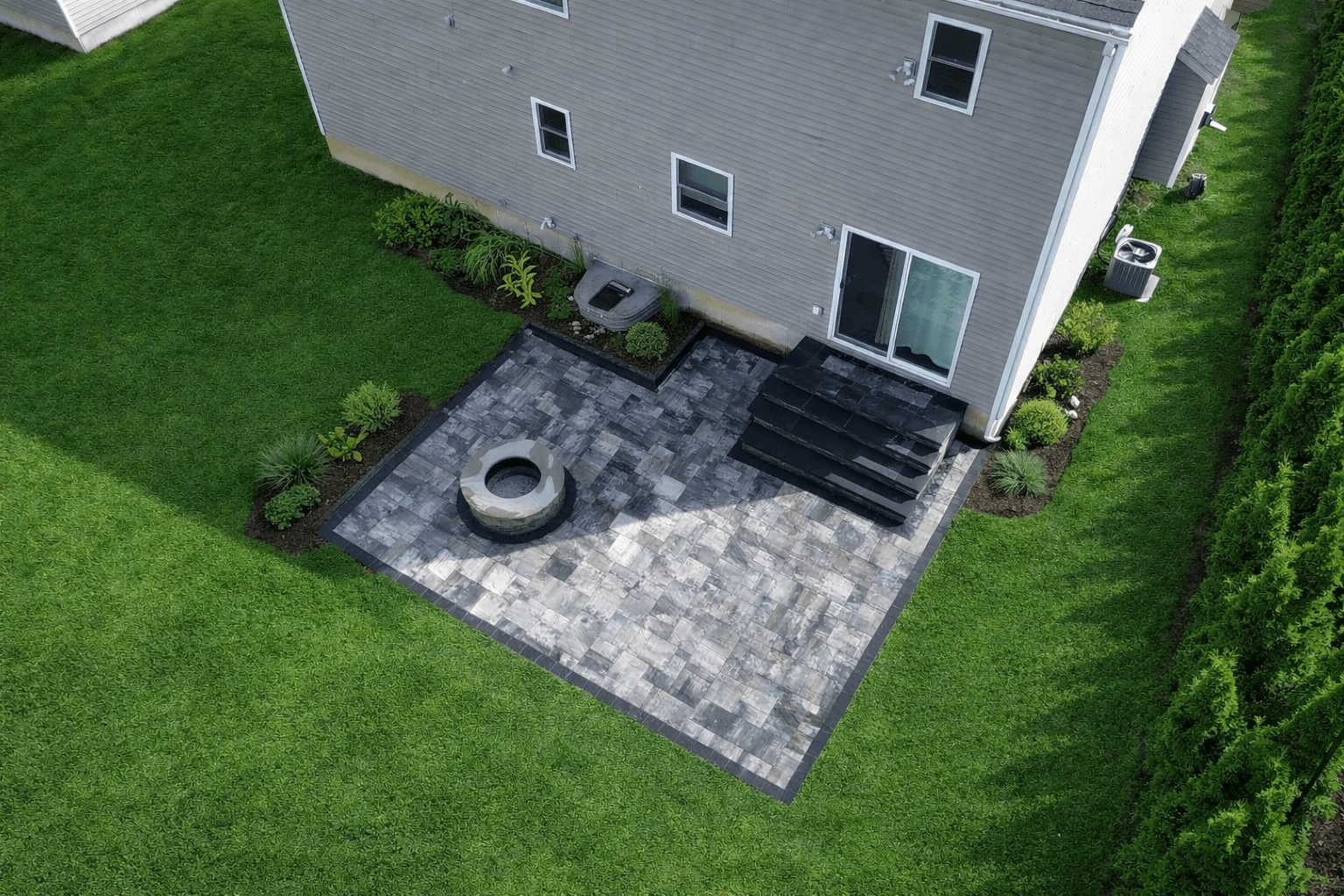 Overhead view of small backyard patio with stone pavers, fire pit, and entry steps