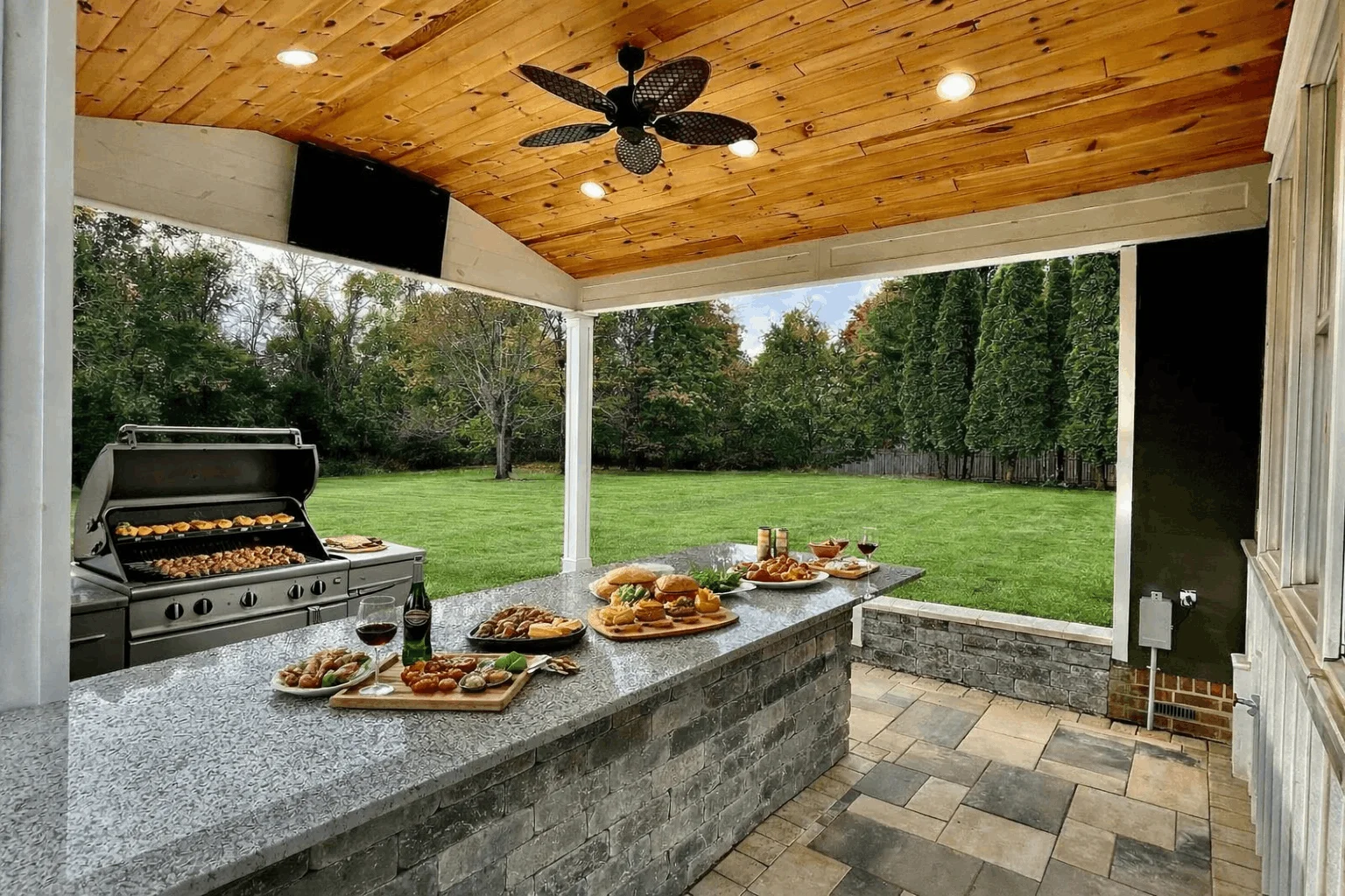 Outdoor living space with covered patio, built-in grill, and stone paver kitchen island