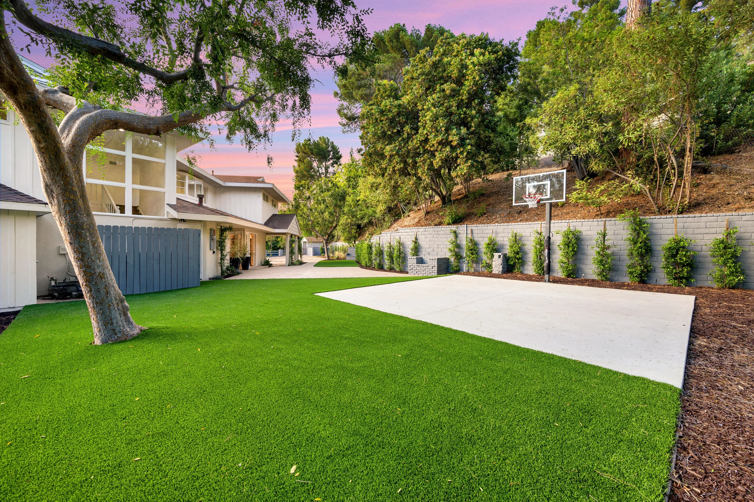 Backyard basketball court with artificial turf lawn and landscaped retaining wall