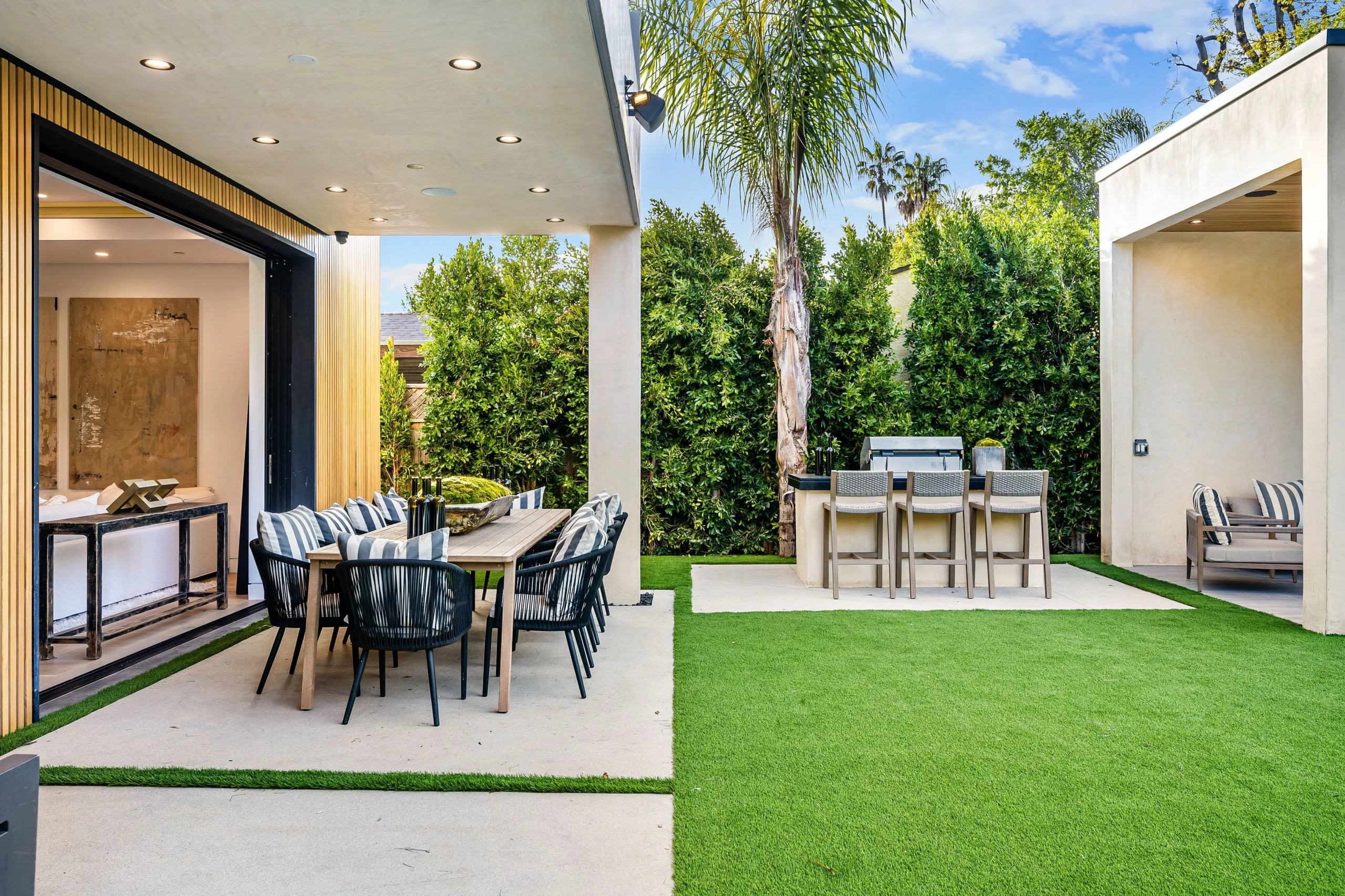 Outdoor dining patio with artificial turf lawn and built-in backyard grill area