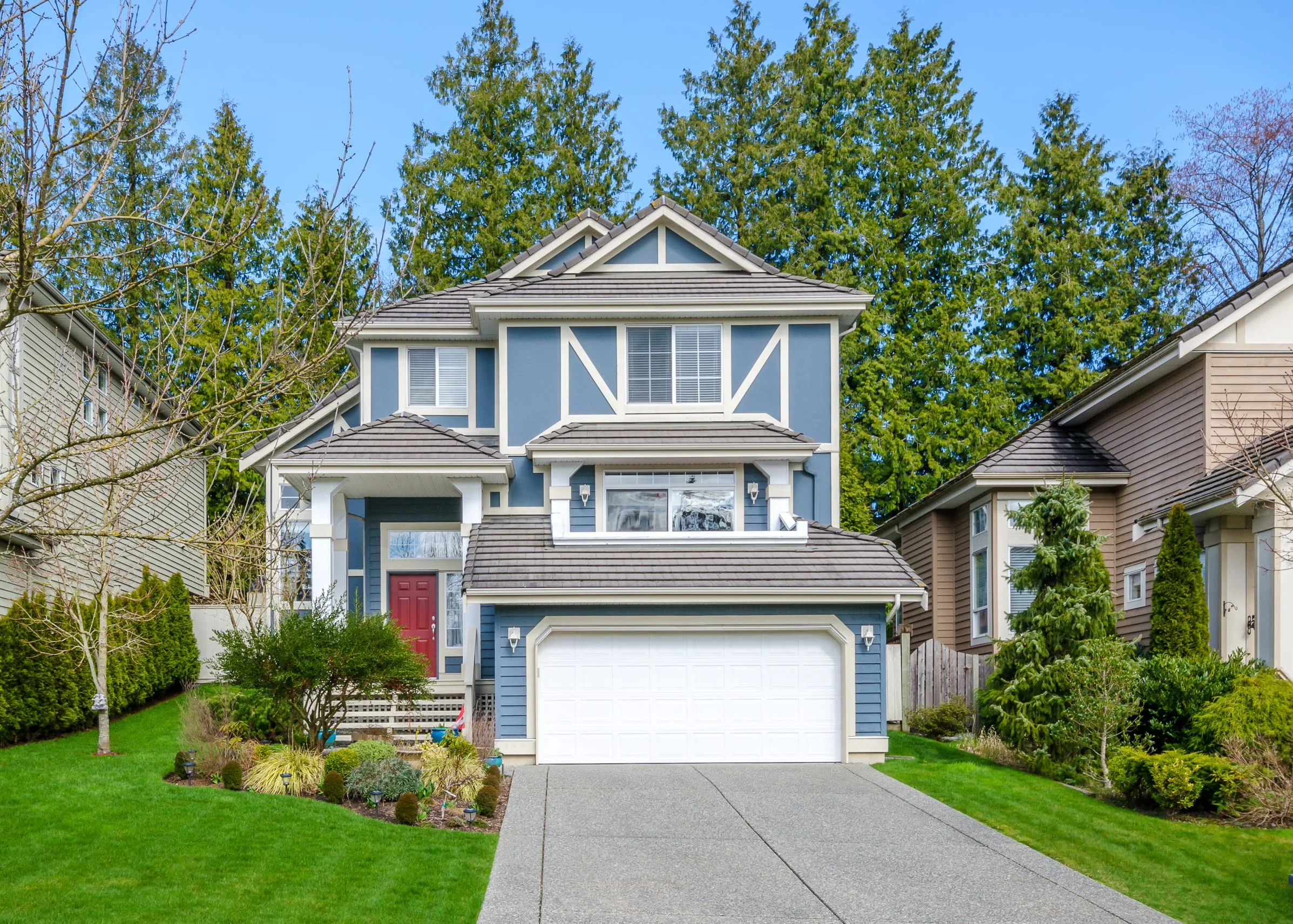 Two-story suburban house with garage, landscaped front yard, and paved driveway.