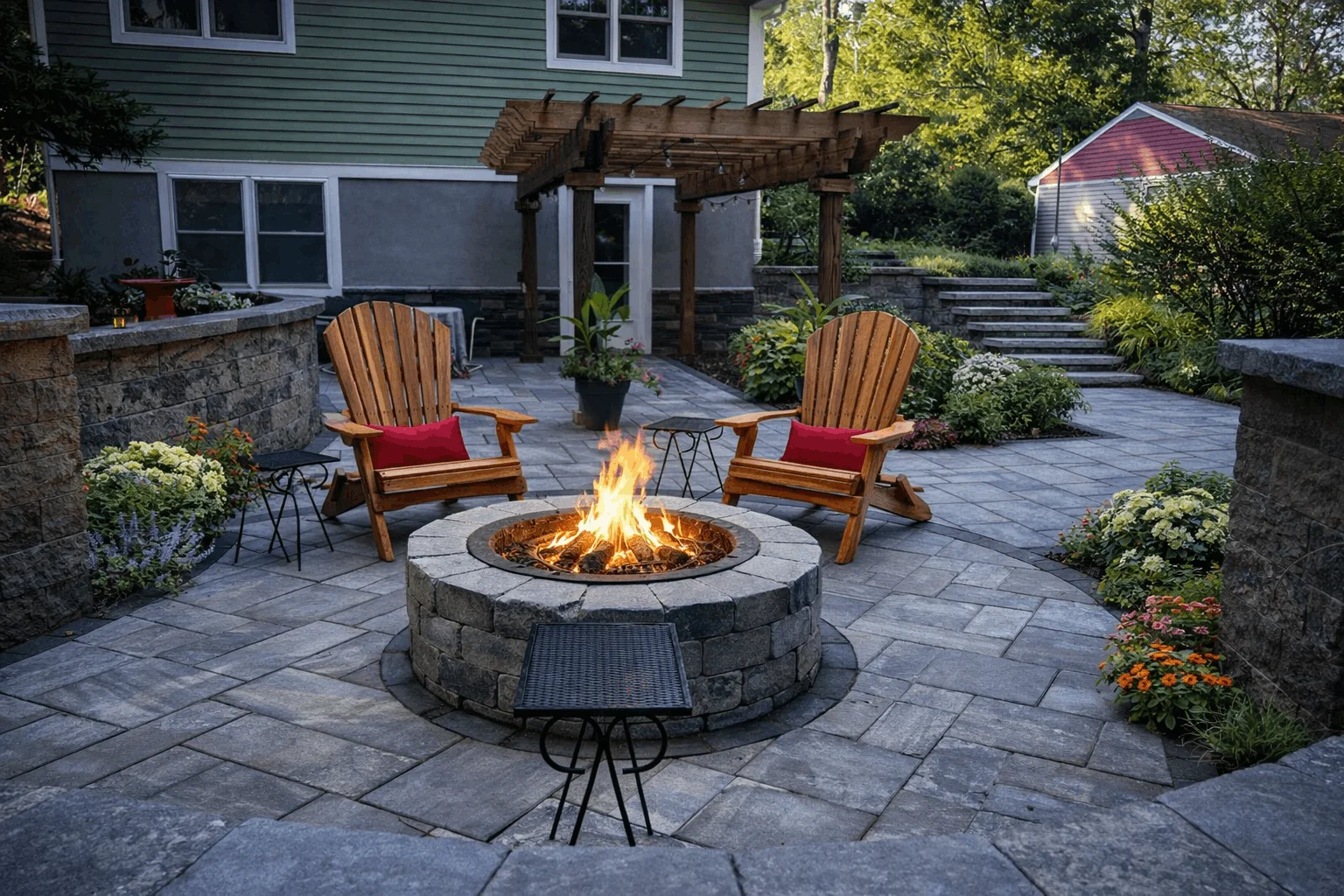 Backyard patio featuring round fire pit, wooden chairs, pergola structure, and decorative plants.