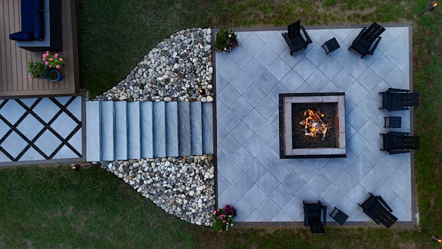 Overhead view of outdoor patio design with fire pit, chairs, stone steps, and decorative rock border.