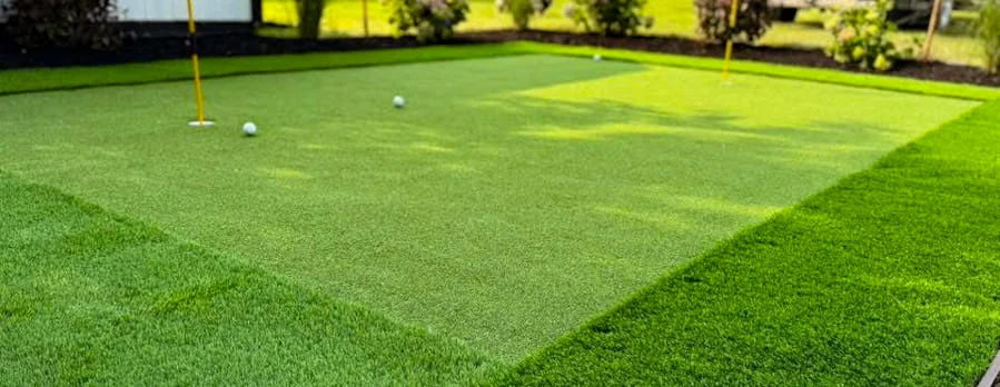 Rectangular backyard putting green with multiple holes and trimmed turf border