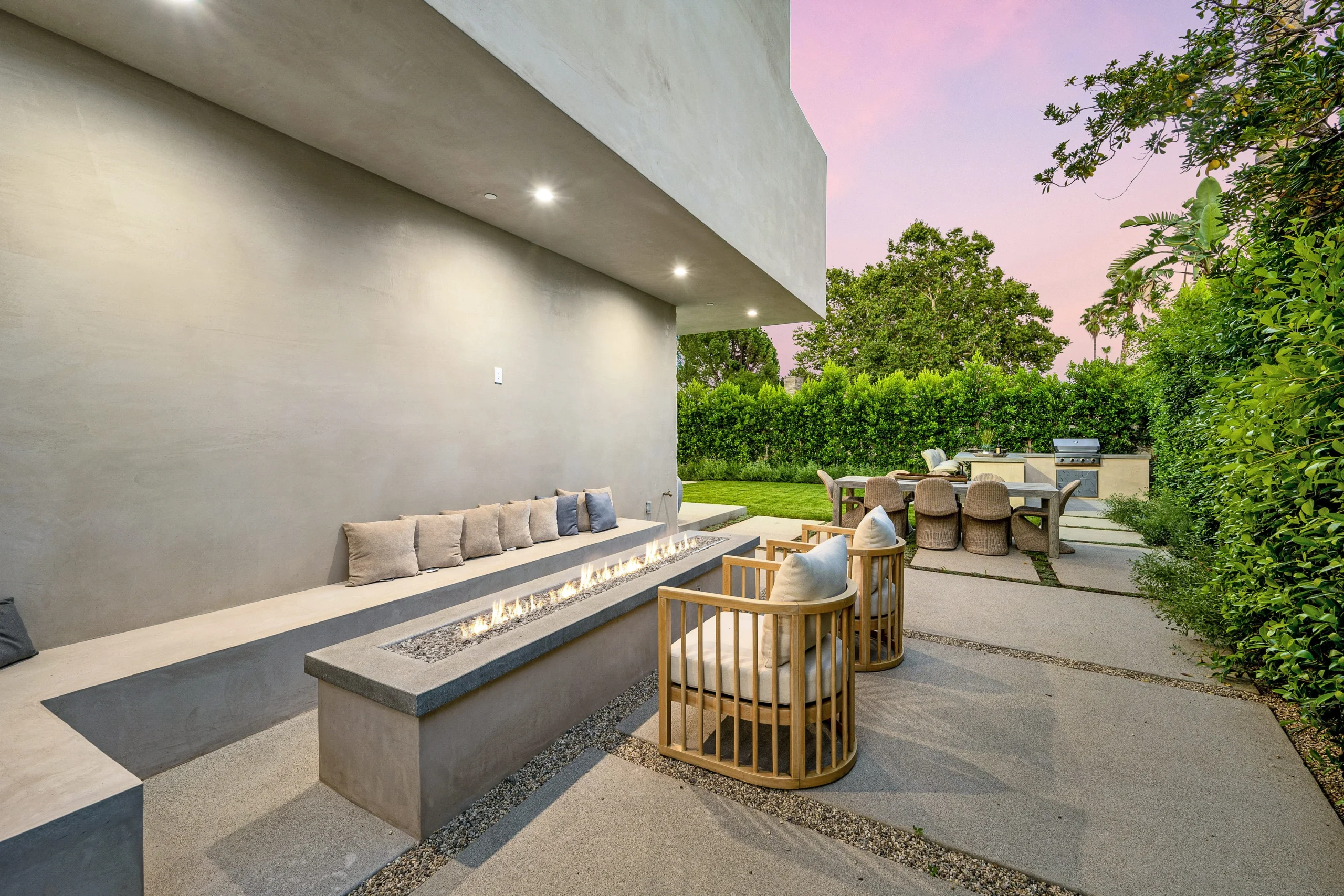 Modern outdoor living space with fire table, seating area, and backyard kitchen patio.
